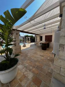 a patio with a white canopy and a potted plant at Villa Assuntina in Cellino San Marco