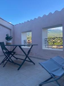 una mesa y sillas en un patio con 2 ventanas en Appartement Bedoin avec vue sur le Mont Ventoux, en Bédoin
