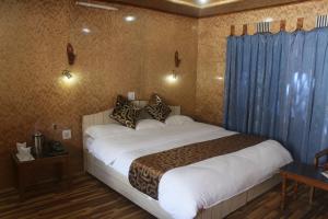 a bedroom with a large bed with blue curtains at Siachen Hotel in Kargil +5 photos
