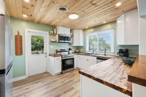 a kitchen with white cabinets and a wooden ceiling at High Seas in DeBordieu Colony home by Peace Vacations in Georgetown