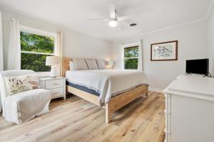 a white bedroom with a bed and a chair at High Seas in DeBordieu Colony home by Peace Vacations in Georgetown