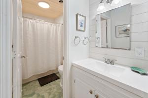 a white bathroom with a sink and a mirror at High Seas in DeBordieu Colony home by Peace Vacations in Georgetown
