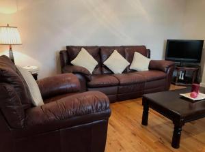 a living room with a brown leather couch and a table at Heatherlea in Donegal