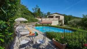 a pool with a table and chairs and a house at Il Boschetto in Radda in Chianti
