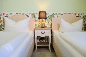 two beds next to each other with a nightstand between them at Anno 1900 Hotel Babelsberg in Potsdam