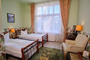 a bedroom with two beds and a chair and a window at Anno 1900 Hotel Babelsberg in Potsdam