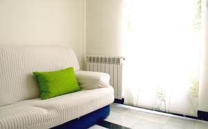 a white couch with a green pillow sitting in front of a window at Casa del Sol y la Luna Apartamento Amanecer in Tíjola