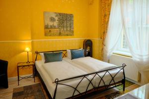 a bedroom with a bed with yellow walls and a window at Anno 1900 Hotel Babelsberg in Potsdam