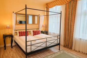a bedroom with a four poster bed with red pillows at Anno 1900 Hotel Babelsberg in Potsdam