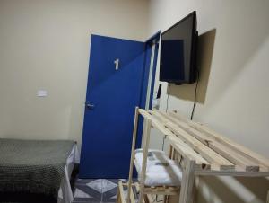 a room with a blue door and a tv at Pousada Li Art in Itapeva