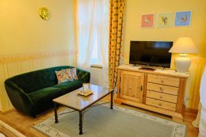 a living room with a green couch and a tv at Anno 1900 Hotel Babelsberg in Potsdam