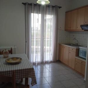 a kitchen with a table and a window with curtains at Anna's Apartment 4 - Sea View stay for 3 in Lixouri in Lixouri