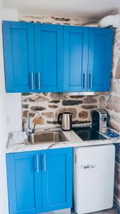 a kitchen with blue cabinets and a sink at Evaggelia's Stone Suites in Skala Marion