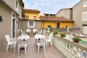 a patio with white tables and chairs on a balcony at Hotel Innocenti in Montecatini Terme