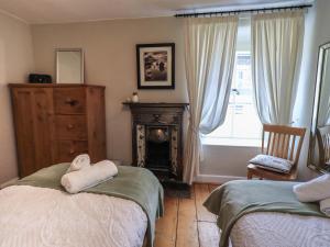 1 Schlafzimmer mit 2 Betten, einem Kamin und einem Fenster in der Unterkunft Brook Cottage in Windermere