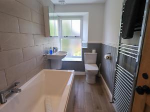 ein Badezimmer mit Badewanne, Toilette und Waschbecken in der Unterkunft Brook Cottage in Windermere + 19 Fotos