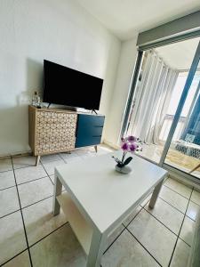een woonkamer met een witte tafel en een tv bij Appart A l'abordage Sète, Gare, parking in Sète