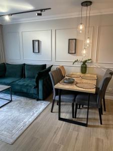 Una sala de estar con un sofá verde y una mesa. en Apartamenty na wydmach RB, en Międzywodzie