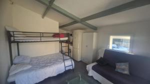a bedroom with a bunk bed and a couch at Maisonnette avec jardin et piscine privée in Grabels