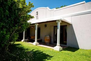 a white house with columns and a grass yard at Camderest House in Graaff-Reinet