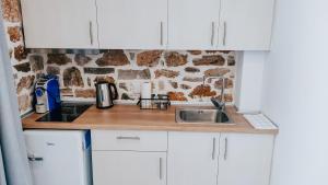 a kitchen counter with a sink and a stone wall at Evaggelia's Stone Suites in Skala Marion