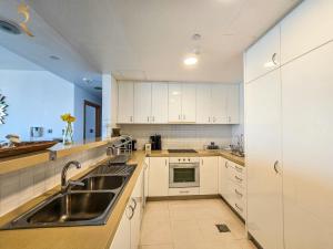 a kitchen with white cabinets and a sink at Al Raha Serenity - Spacious 2BR Getaway Near Yas Island & Al Raha Beach in Abu Dhabi