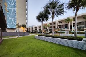 a large building with palm trees in front of it at Al Raha Serenity - Spacious 2BR Getaway Near Yas Island & Al Raha Beach in Abu Dhabi