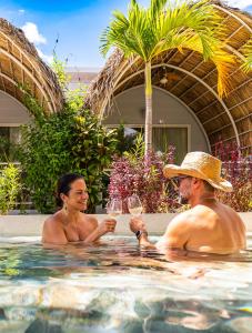 a man and woman sitting in a swimming pool with wine glasses at Les Voiles Blanches - Luxury Lodge in Tamarindo