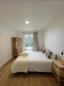 a bedroom with a large white bed and a window at Ribeira Roots Residence in Santa Cruz
