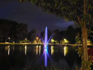 a fountain in the middle of a lake at night at Aquarius Stawy 3 in Grodzisk Mazowiecki