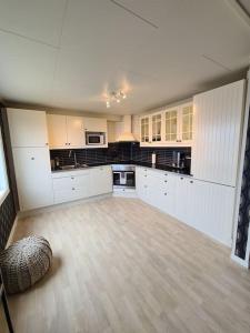 cocina grande con armarios blancos y suelo de madera en Casa Melkhaugen, en Veiholmen