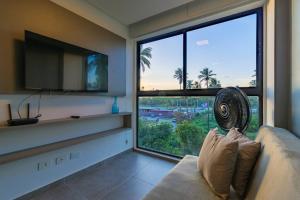 a living room with a couch and a large window at Marina do Cupe 302 in Porto De Galinhas