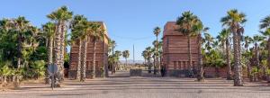a row of palm trees in front of a building at Villa confortable et familiale de 458 m2 avec piscine privée au cœur du domaine des jardins de lAtlas à Marrakech in Sraghna