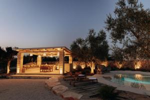 a gazebo with a table and benches next to a pool at Trullo Amiura B&B in Corato
