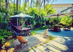 a patio with a hammock and tables and umbrellas at Tombo Beach Home Stay in Guarujá