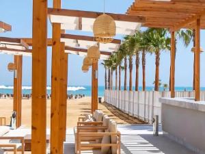 Un bar de playa con palmeras y el océano. en Whispering Waters Two Bedroom with a Garden Azha, en Ain Sokhna