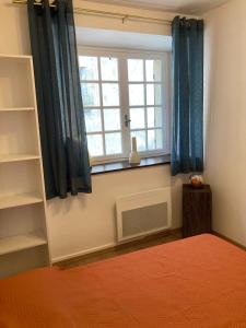 a bedroom with a bed and a window with blue curtains at Maison 2 chambres avec cour intérieure in Alet-les-Bains +7 photos