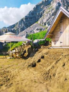 a building and an umbrella on a dirt field at Lake house Draskovici in Kolašin