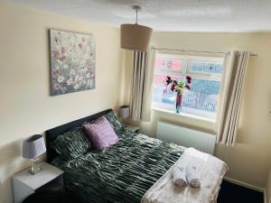 a bedroom with a bed and a vase of flowers in a window at Cozy 2 bed house oldham 10 miles to Manchester City centre wifi included in Oldham +11 photos