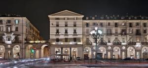 a large white building at night with a green light at Piazza Vittorio Suites in Turin