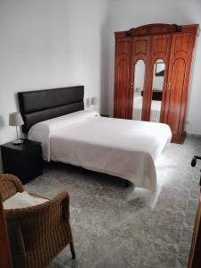 a bedroom with a white bed and a wooden cabinet at Casa Esperanza in Arinaga