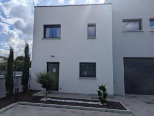 a white house with two garage doors on it at Maison TESLA aéroport gare cnpe rte Golf de Lyon in Jons