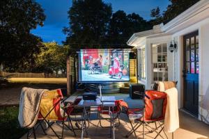 a patio with a table and chairs and a tv at Brookwood Getaway Stock Tank Pool Outdoor Theater in Franklin
