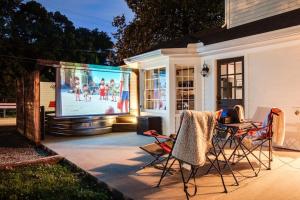a patio with a table and chairs and a large screen at Brookwood Getaway Stock Tank Pool Outdoor Theater in Franklin