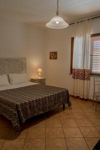 a bedroom with a bed and a table and a window at B&B Il Corbezzolo in Posada