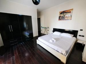 a bedroom with a large white bed and black cabinets at Lux Apartment in Vlorë