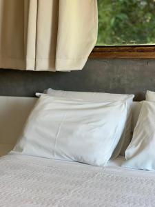 a white pillow sitting on a bed with a window at Yannai Chalé Praia in Ilhabela +52 photos
