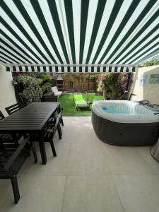 a large hot tub sitting on a patio with a table at Relaxing Garden Los Cristianos con Jacuzzi y Barbacoa in Arona