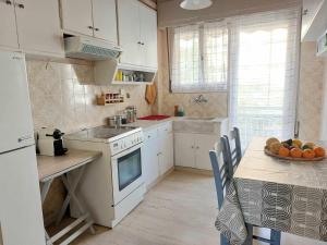 a kitchen with white cabinets and a table with a bowl of fruit at Ήσυχο φωτεινό δωμάτιο με βεράντα in Athens +1 photo