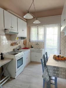 a kitchen with white cabinets and a table with a bowl of fruit at Ήσυχο φωτεινό δωμάτιο με βεράντα in Athens